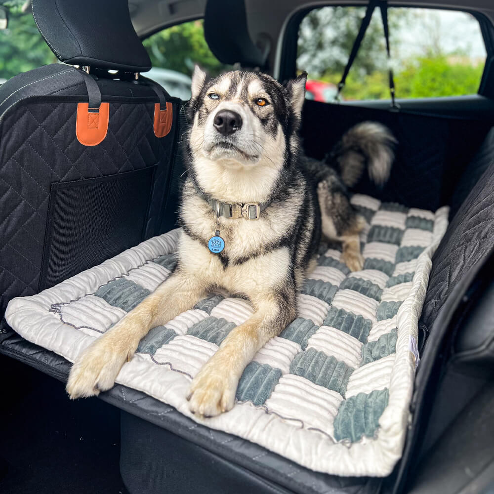 Dog lying comfortably on anti-slip gray plaid car bed mat