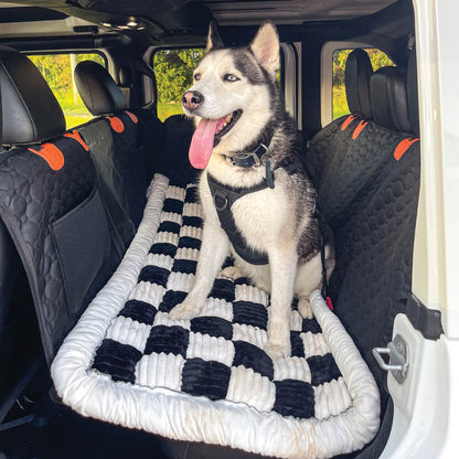 Husky sitting on black plaid dog car bed mat