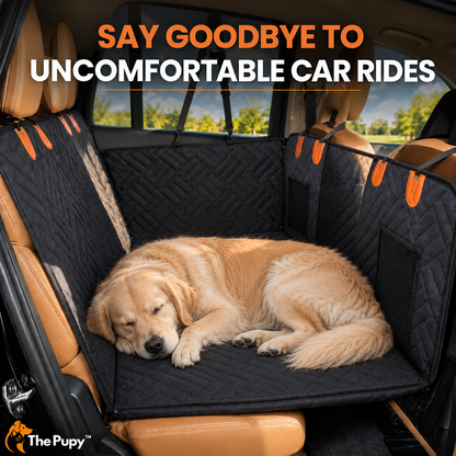 A golden retriever dog rests asleep on a black quilted car seat cover installed inside a tan vehicle. The cover includes orange accent tabs and side mesh pockets. Large promotional text at the top reads, 'SAY GOODBYE TO UNCOMFORTABLE CAR RIDES'. The 'The Pupy' brand logo appears in the bottom-left corner.
